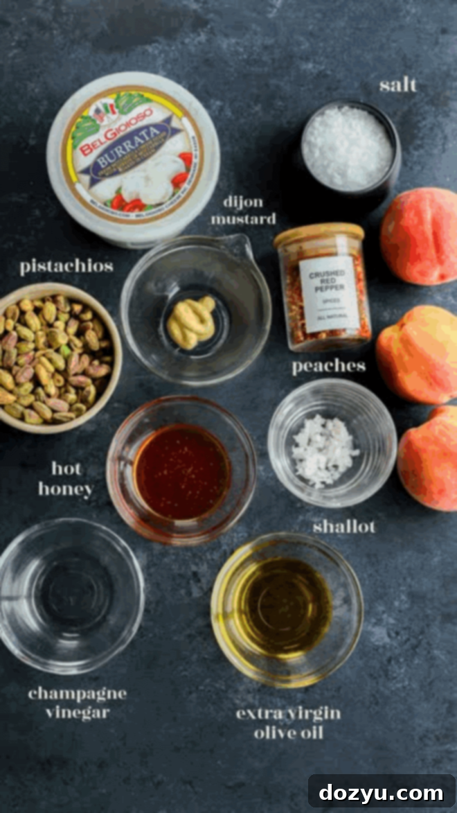 Velvety Burrata with Sun-Ripened Peaches 3 Top-down view of ingredients on a dark surface: burrata cheese, pistachios, hot honey, Dijon mustard, champagne vinegar, extra virgin olive oil, salt, crushed pepper, shallot, and two fresh peaches.