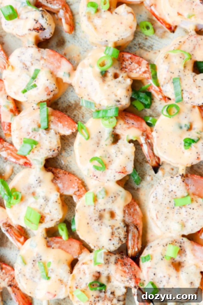 Sizzling Bang Bang Prawns 2 Bang bang shrimp grilled on skewers on a platter, garnished with fresh green onions