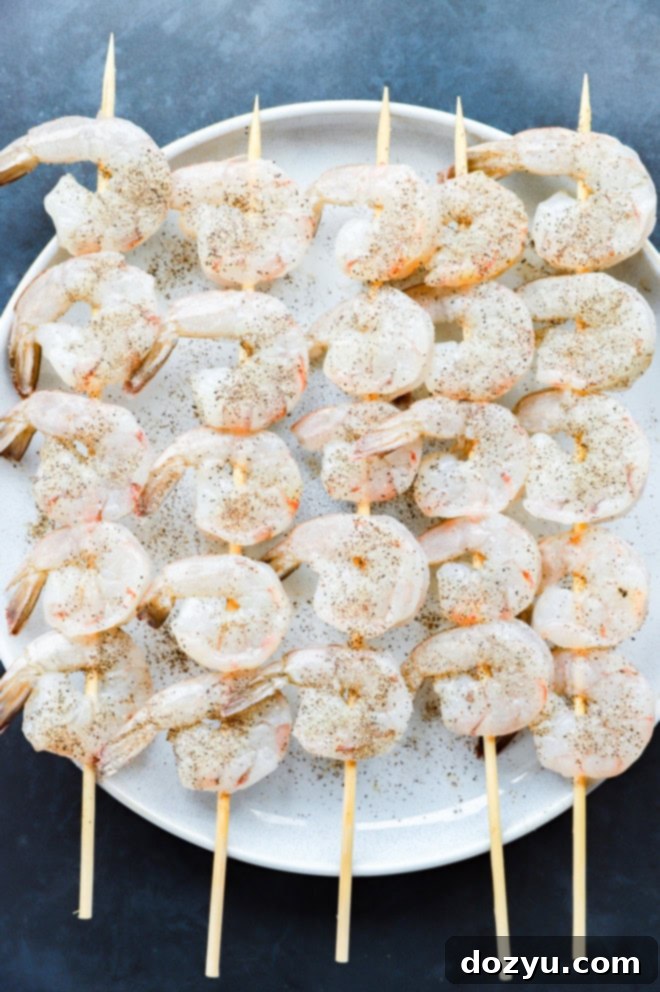 Sizzling Bang Bang Prawns 6 Seasoned shrimp skewers neatly arranged on a plate, ready for grilling.