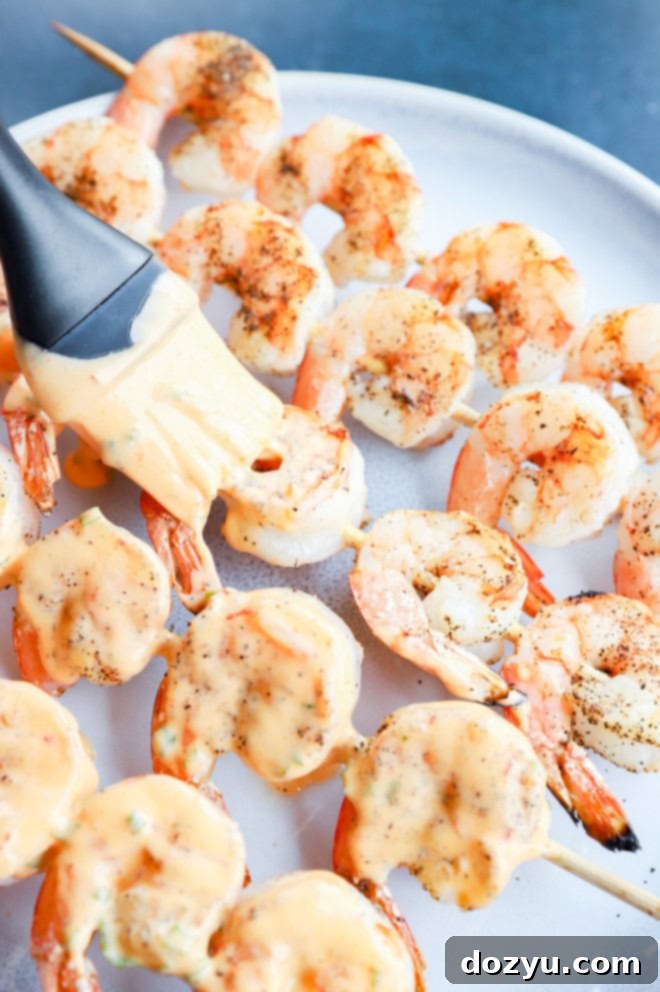 Sizzling Bang Bang Prawns 8 Brushing the creamy bang bang sauce onto grilled shrimp skewers on a platter.