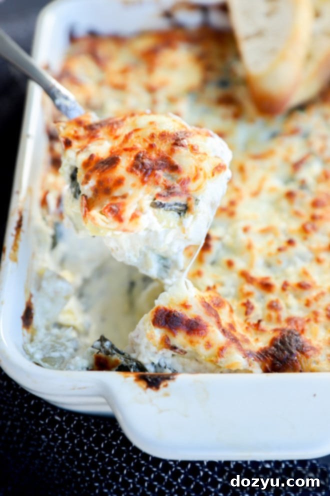 Artichoke Spinach Goat Cheese Delight 2 Spoon with hot cheesy dip with spinach and artichoke