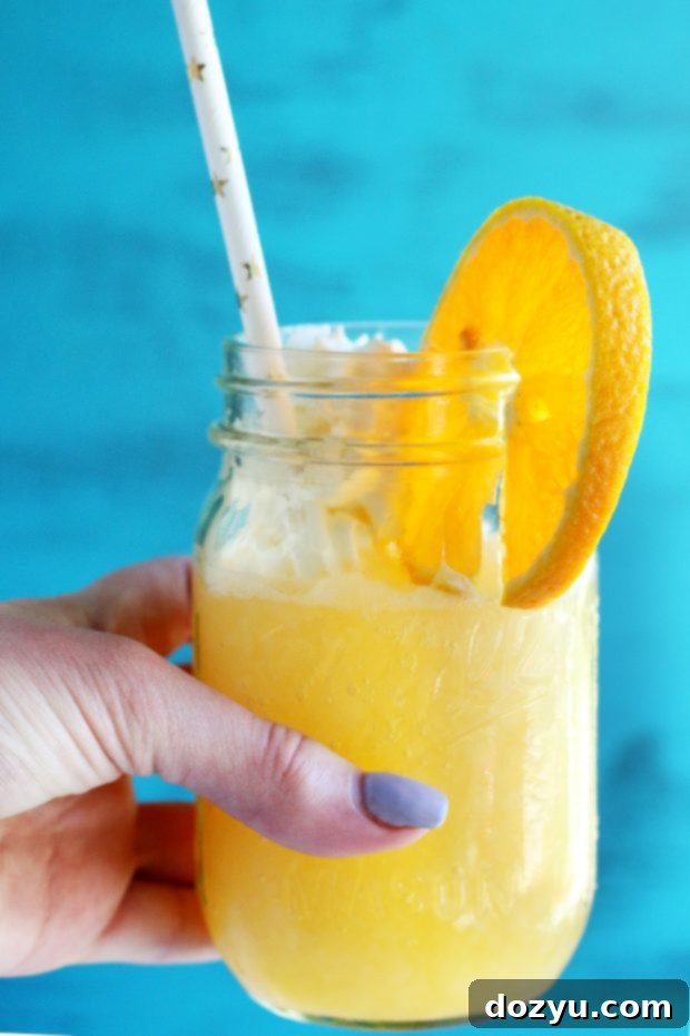 Hand holding an orange dreamsicle with orange and whipped cream