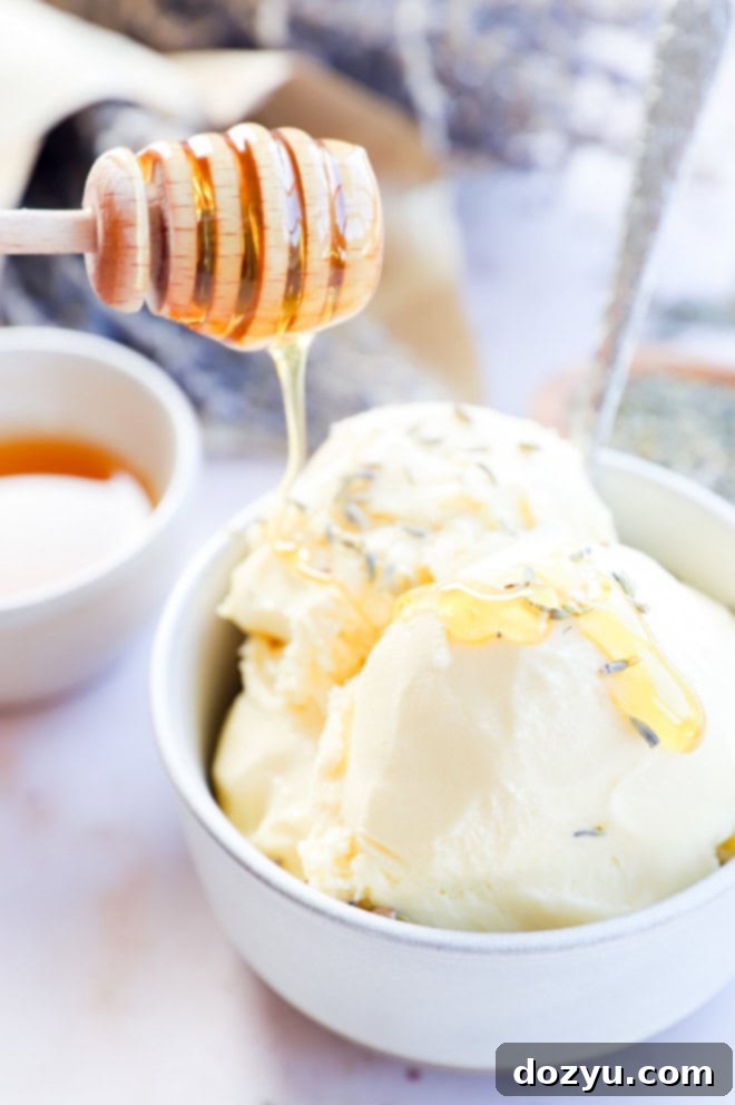 Drizzling golden honey over a bowl of lavender honey ice cream, garnished with fresh flowers, alongside a spoon