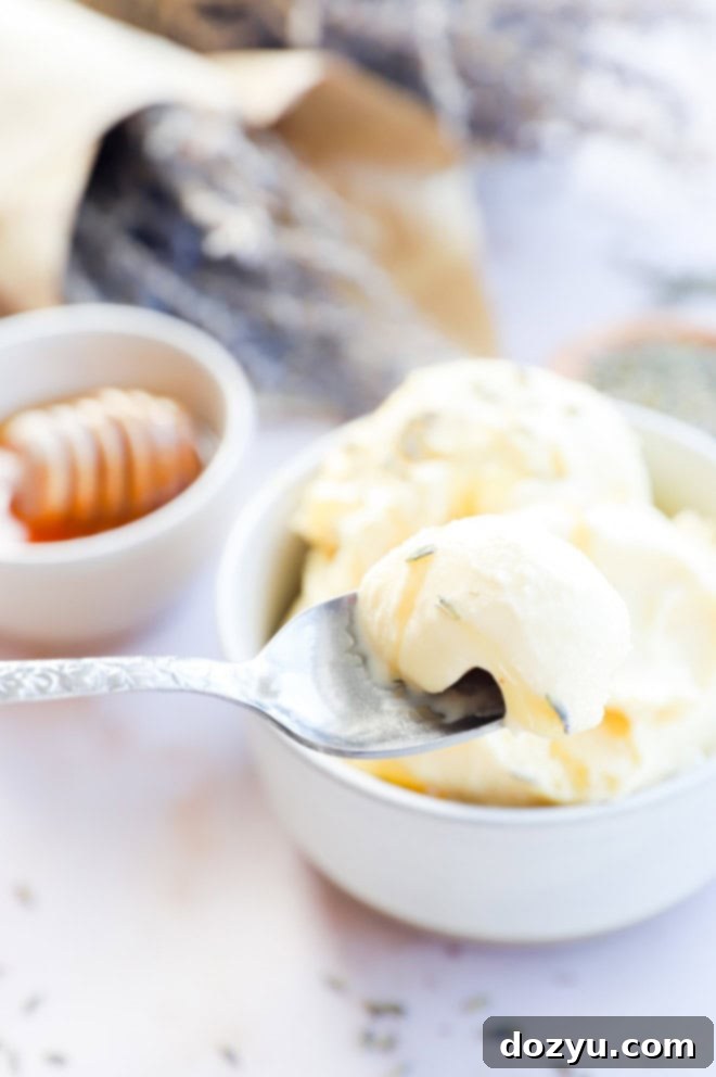 A close-up of a spoon scooping creamy, homemade lavender honey ice cream from a bowl, with a soft focus on surrounding fresh flowers