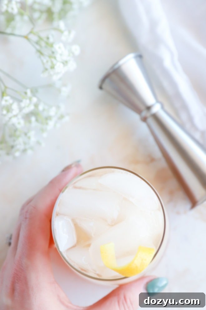 Hand holding a gin cocktail overhead image with a lemon twist