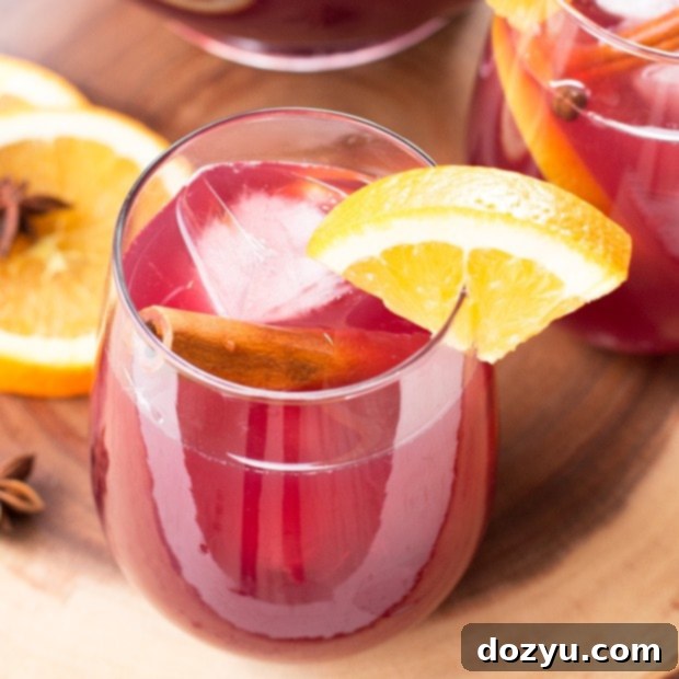 Big Batch Holiday Sangria in a clear pitcher with sliced fruit