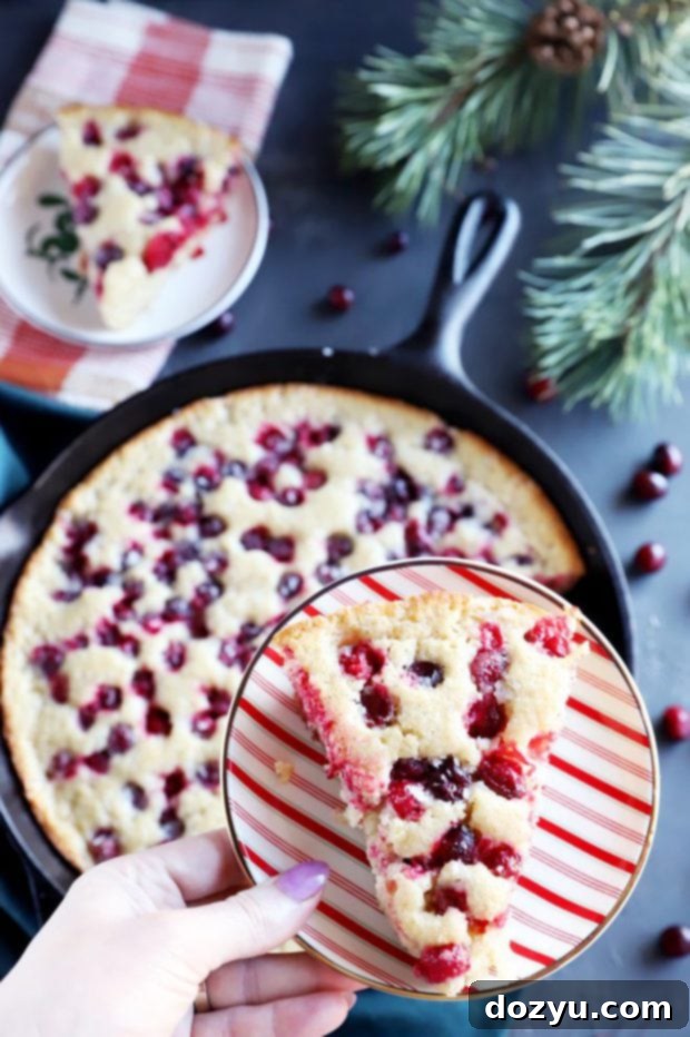 Yuletide Cranberry Cobbler 3 Holiday dessert slice of cranberry cobbler on a white plate with a fork.
