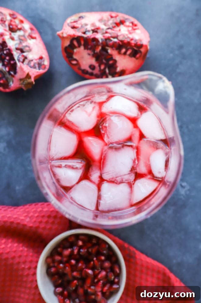 Hands stirring a Pomegranate Negroni in a mixing glass with a bar spoon.