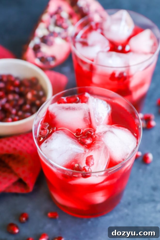 Pomegranate cocktail in stylish glasses with fresh pomegranate seeds on a festive table.