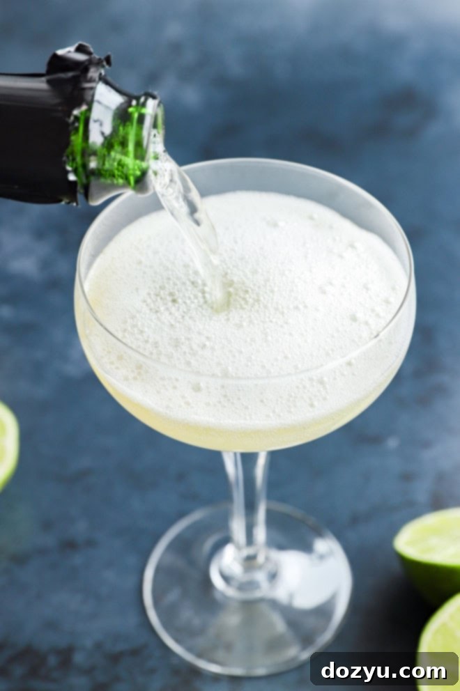 Pouring sparkling champagne into an elegant coupe glass, ready for an elderflower cocktail
