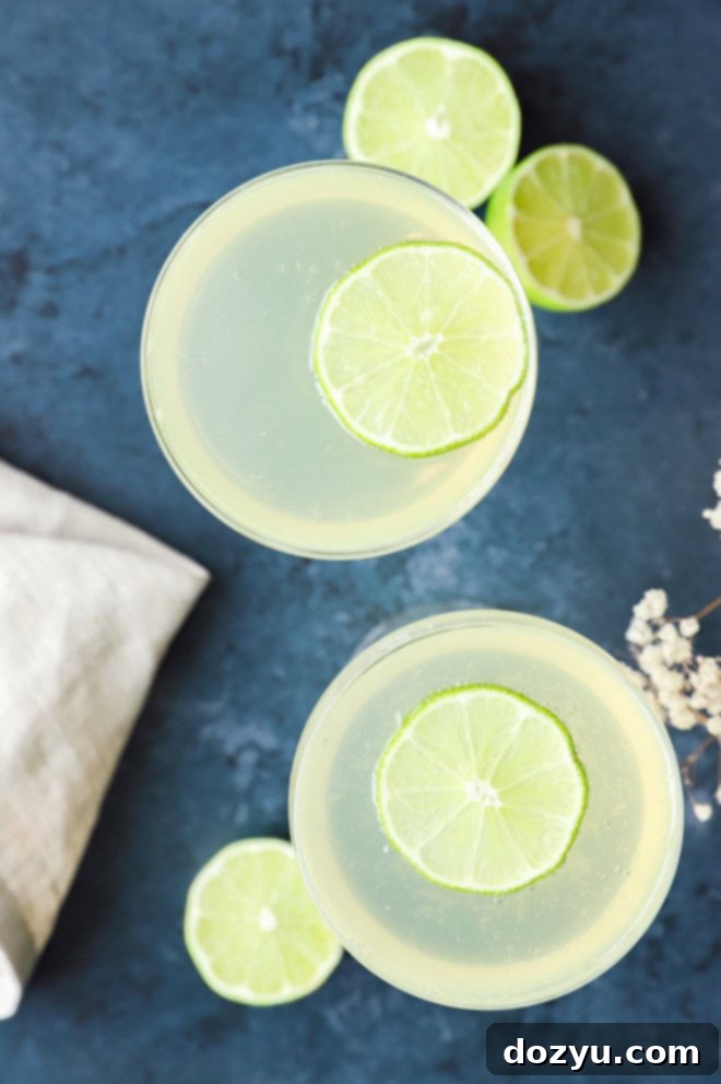 Sparkling elderflower cocktail in elegant coupe glasses, adorned with fresh limes