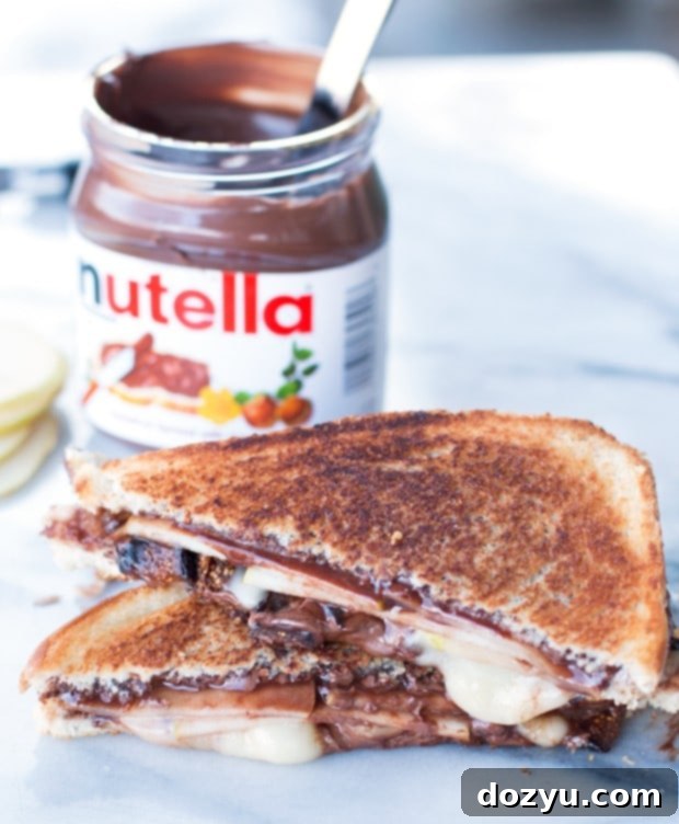 A close-up view of a sweet and savory grilled sandwich, showcasing vibrant layers of Nutella, creamy Brie, fresh pear, and sliced figs.
