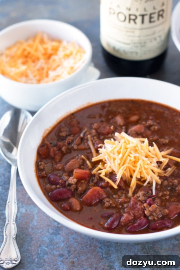 A steaming bowl of Black Porter Chili topped with shredded cheese and fresh cilantro, ready to be enjoyed.