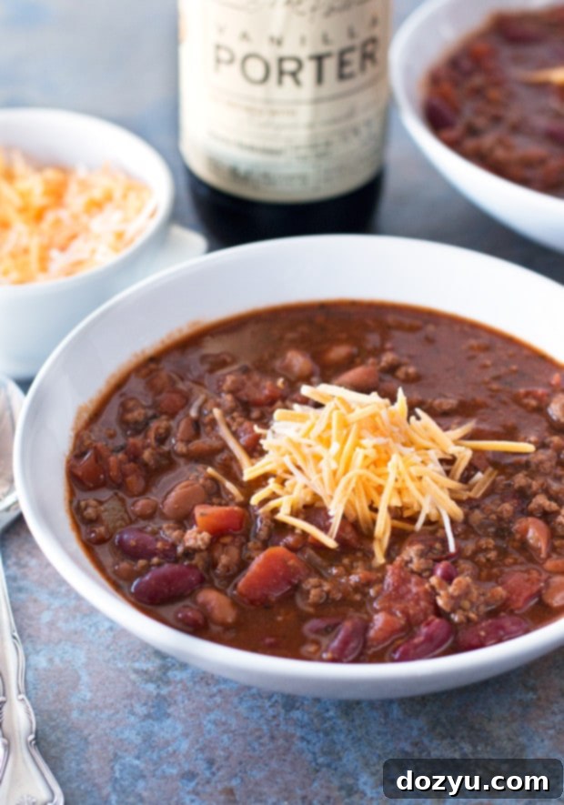 A beautifully presented bowl of Black Porter Chili, garnished with cheese, sour cream, and fresh herbs.