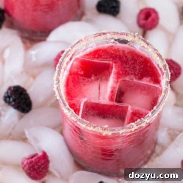 Close up of a Mixed Berry Margarita in a glass with a sugar rim and fresh berries