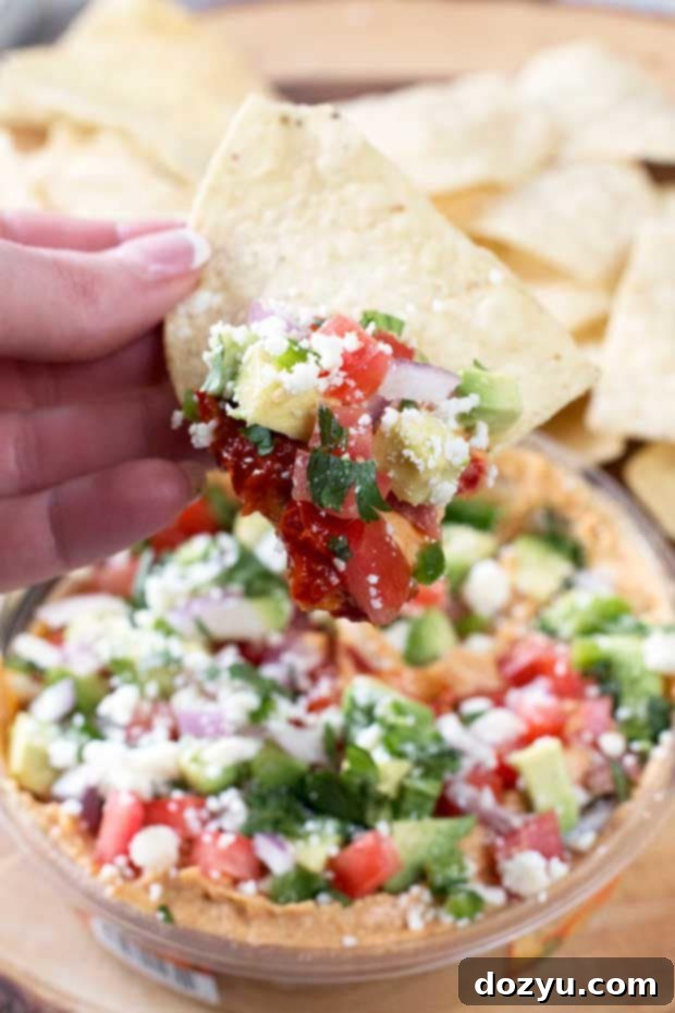 Individual ingredients for South of the Border Hummus, including Sabra Chipotle Hummus, red onion, tomato, jalapeño, avocado, cilantro, and cotija cheese.