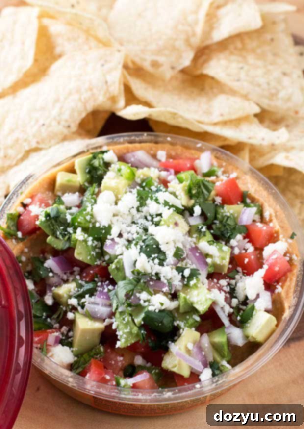A beautifully arranged platter of South of the Border Hummus with Sabra, surrounded by a variety of crispy tortilla chips, ready for dipping.