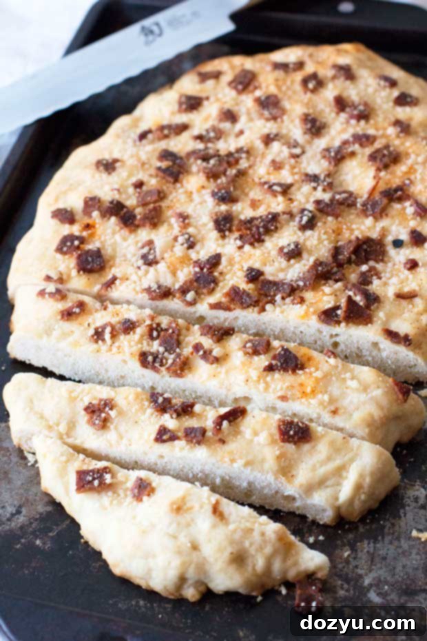 A whole loaf of golden-brown Bacon Parmesan Quick Bread, with visible bacon bits and grated parmesan cheese on top, resting on parchment paper.