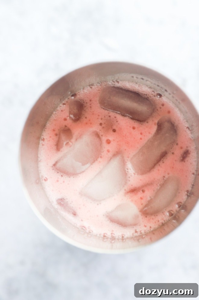 Overhead close-up image of a cocktail shaker filled with ice and ingredients for a pomegranate margarita.
