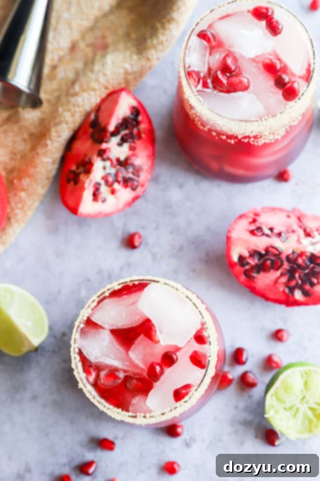 An overhead view of two pomegranate margaritas in glasses, ready to be served.