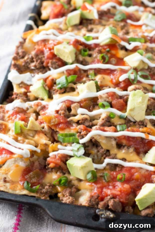 Ultimate Loaded Nachos 3 Close-up of extra spicy loaded nachos with abundant melted cheese and red chili peppers