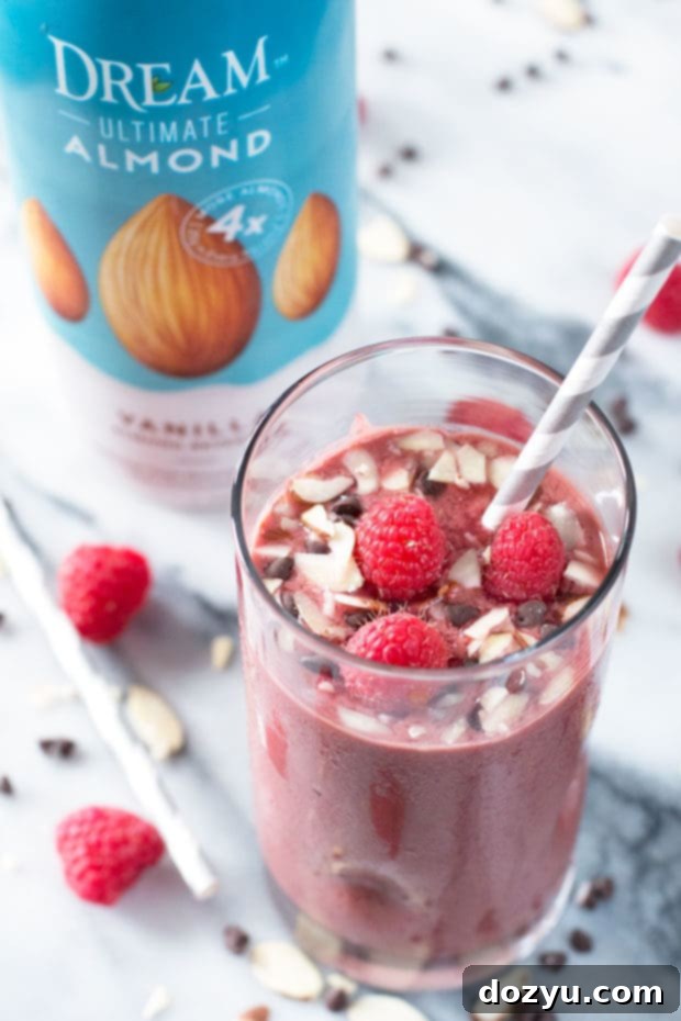 A glass of Boozy Chocolate-Covered Raspberry Smoothie garnished with almonds and chocolate chips