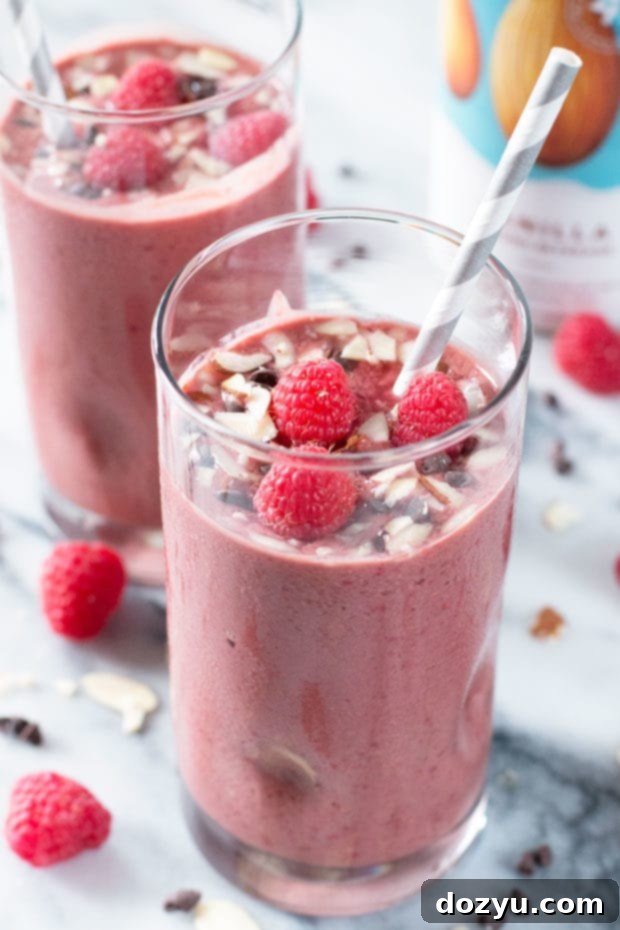 Two glasses of Boozy Chocolate-Covered Raspberry Smoothies garnished with fresh fruit