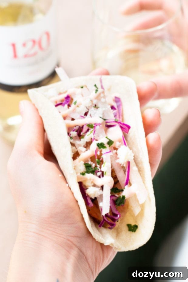 Overhead shot of two Grilled Bacon-Wrapped Shrimp Tacos on a white plate with fresh ingredients | cakenknife.com