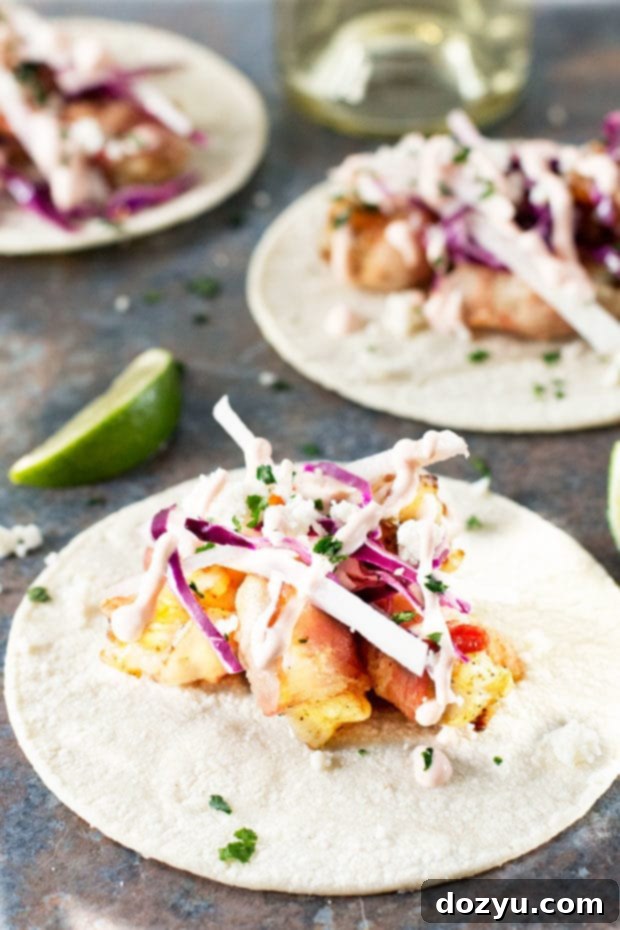 A vibrant platter of Grilled Bacon-Wrapped Shrimp Tacos with fresh garnishes and lime wedges | cakenknife.com