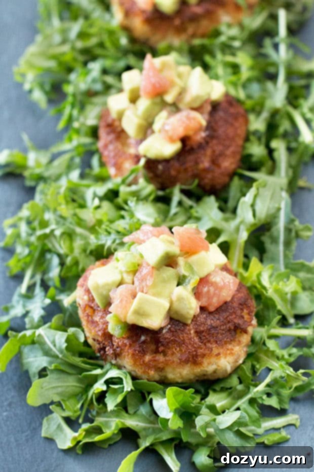 A plate of Crispy Crab Cakes served beautifully with a side of bright Avocado Grapefruit Salsa, showcasing a perfect balance of savory and zesty flavors.