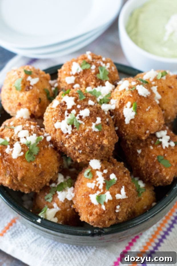Golden brown Mexican Arancini on a plate with a side of green avocado cilantro dipping sauce
