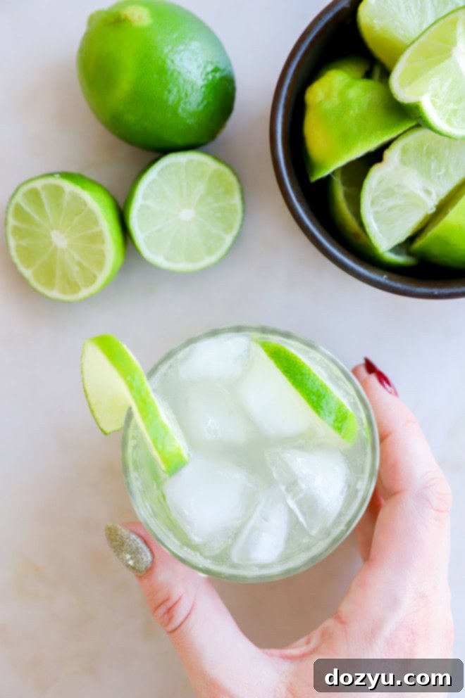 hand holding a glass filled with a caipirinha cocktail