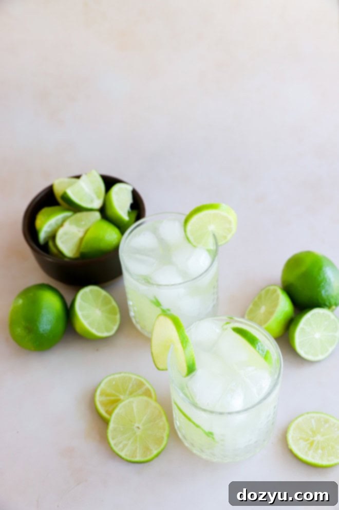 glasses of caipirinha with a bowl of fresh lime wedges and whole limes in the background