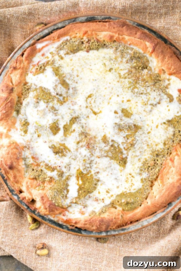 Close-up of freshly baked Pistachio Pesto Pizza, showcasing the vibrant green pesto, creamy crème fraîche, and golden-brown crust.