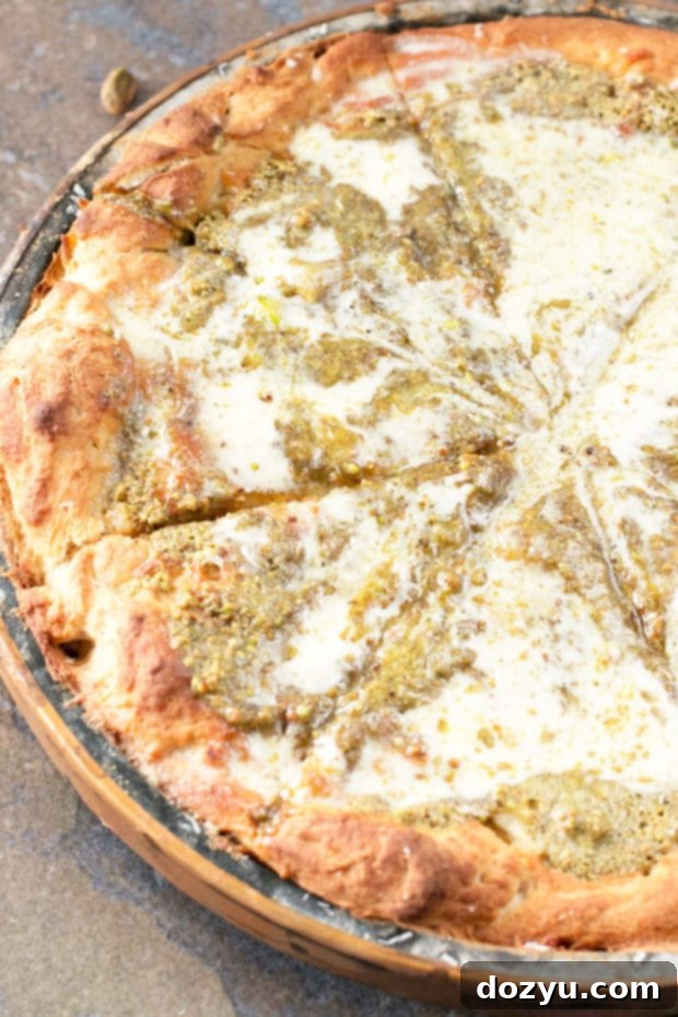 A slice of Pistachio Pesto Pizza with crème fraîche, roasted garlic, and melted mozzarella, ready to be enjoyed.