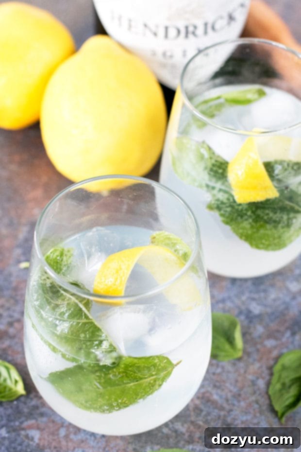 Lemon Basil Gin & Tonic with square ice cubes and a garnish of lemon and basil