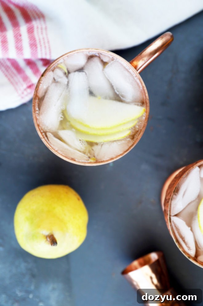 Two Moscow Mules with pear slices in copper mugs, set against a cozy winter backdrop.