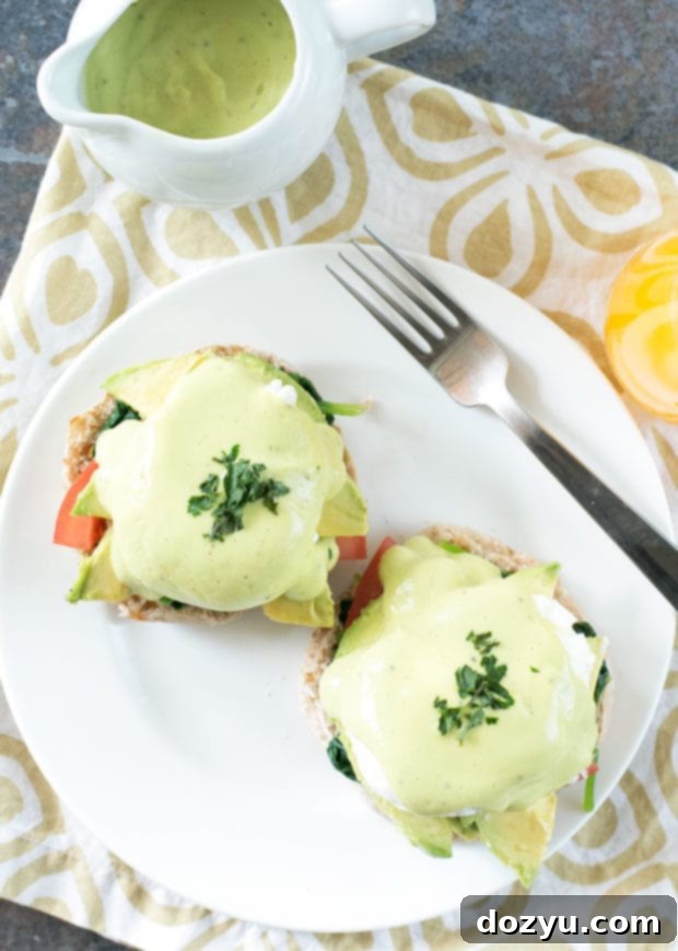 Close-up of California-Style Eggs Benedict with avocado slices and creamy sauce.