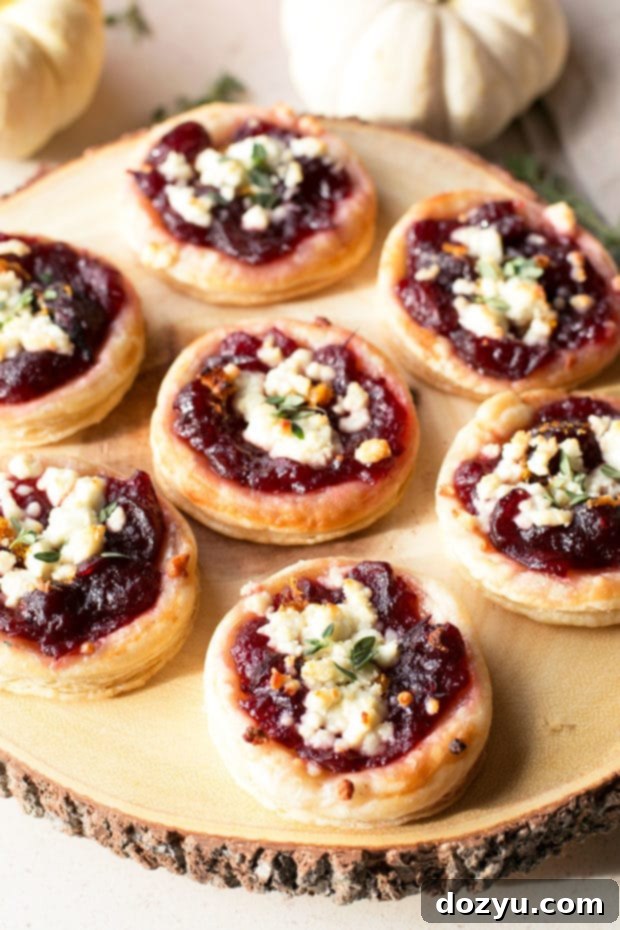 Ruby Red & Creamy Bites 2 Close-up of golden brown cranberry goat cheese tarts on a rustic board, garnished with fresh thyme.