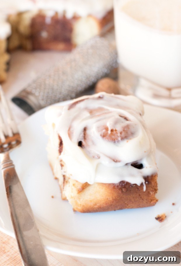 A single Egg Nog Cinnamon Roll being pulled from the pan, showing its gooey center