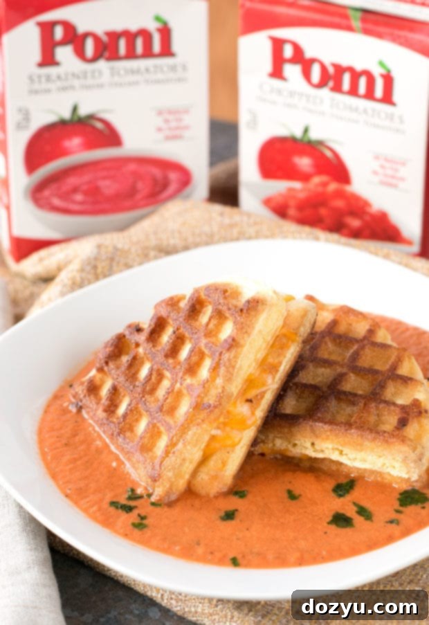 A full spread of Cornbread Waffle Grilled Cheese quarters and a steaming bowl of Tomato Basil Soup.
