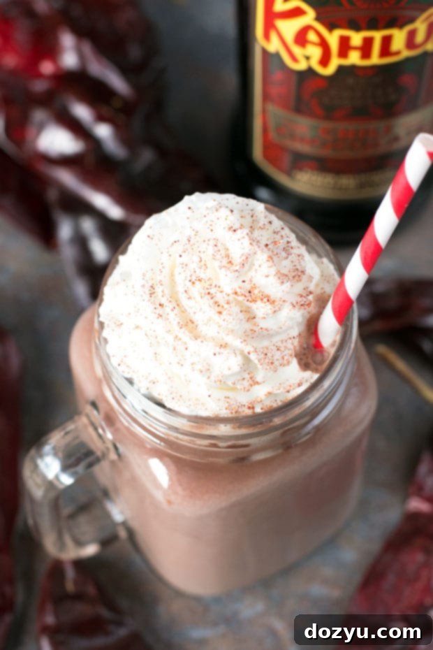 Spicy Spiked Hot Chocolate 5 Artfully arranged Boozy Chili Hot Chocolate on a wooden background, garnished with whipped cream and chili powder