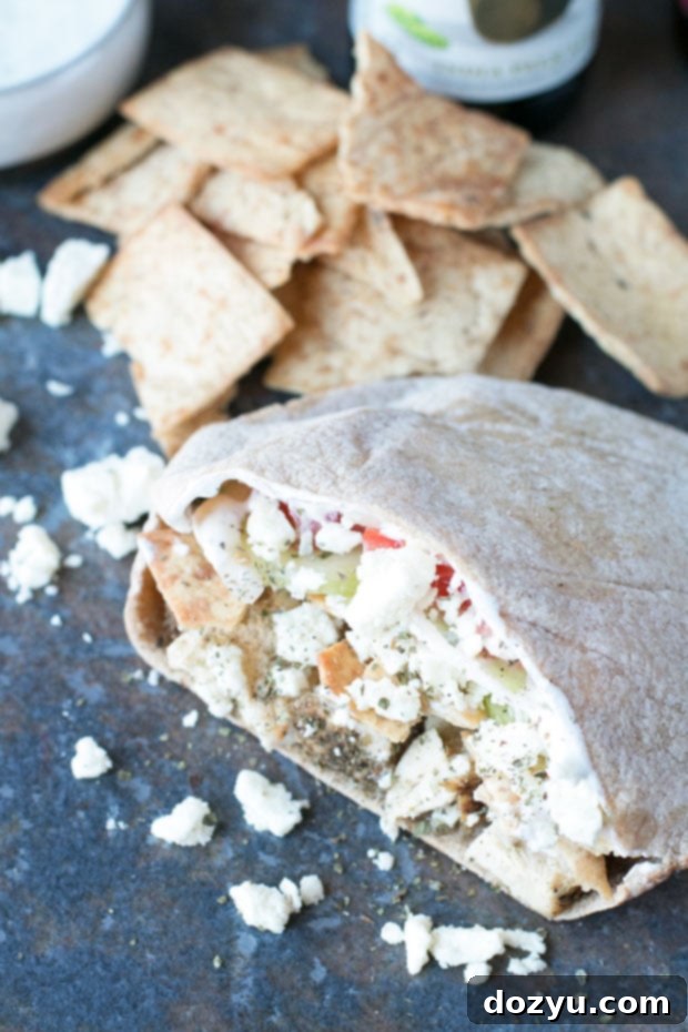 Two halves of a Crunchy Chicken Gyro Sandwich showing the juicy chicken, fresh vegetables, and sauce