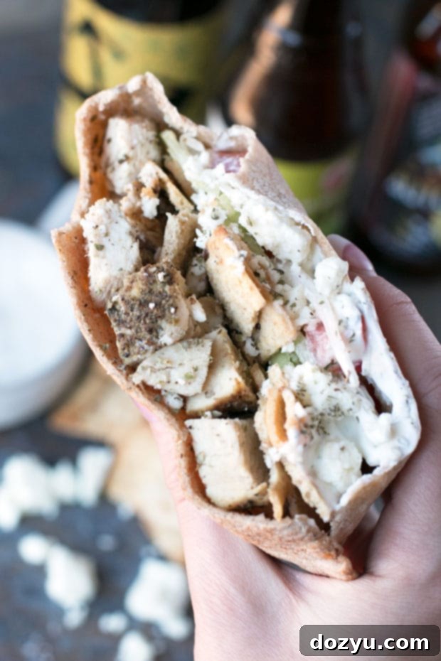 A Crunchy Chicken Gyro Sandwich with a light creamy sauce and fresh herbs on top