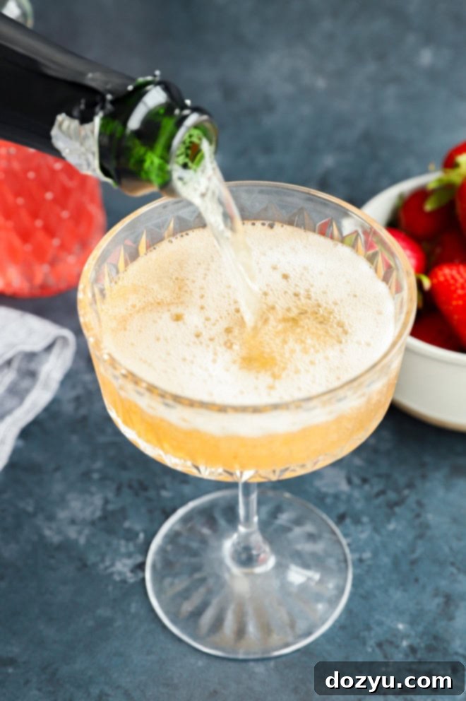 pouring champagne into a coupe glass to make the strawberry champagne cocktail