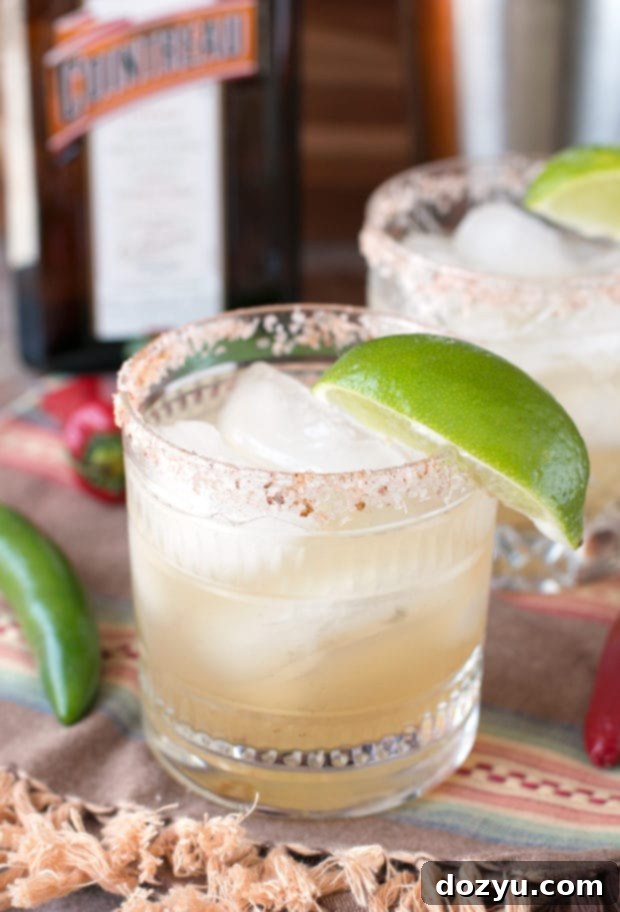 A vibrant Chili Lime Margarita with a festive arrangement of ingredients including sliced chiles and limes.
