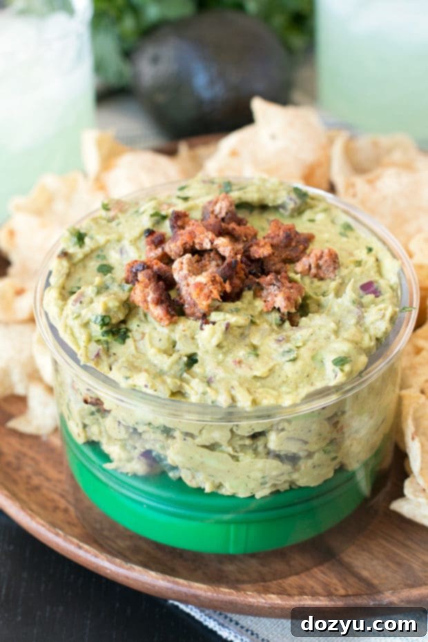 Chipotle Chorizo Guacamole served with tortilla chips, showcasing its vibrant green color and savory chorizo bits.