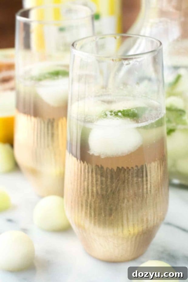 Refreshing Melon Sangria 2 Melon Sangria served in a glass pitcher with melon balls and mint