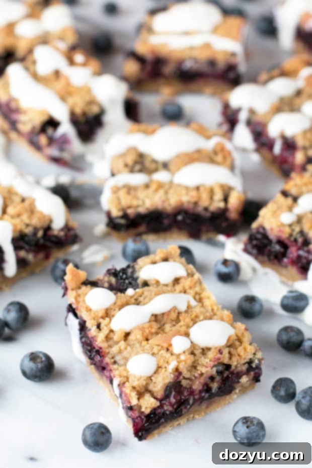 Multiple blueberry pie crumb bars stacked, showcasing their distinct layers