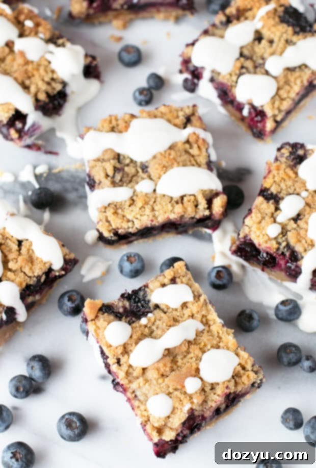 A plate of two blueberry pie crumb bars, one with a lemon drizzle